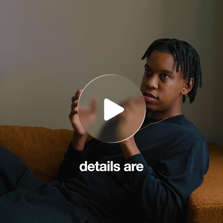 A man reclining on an orange sofa mid-conversation
